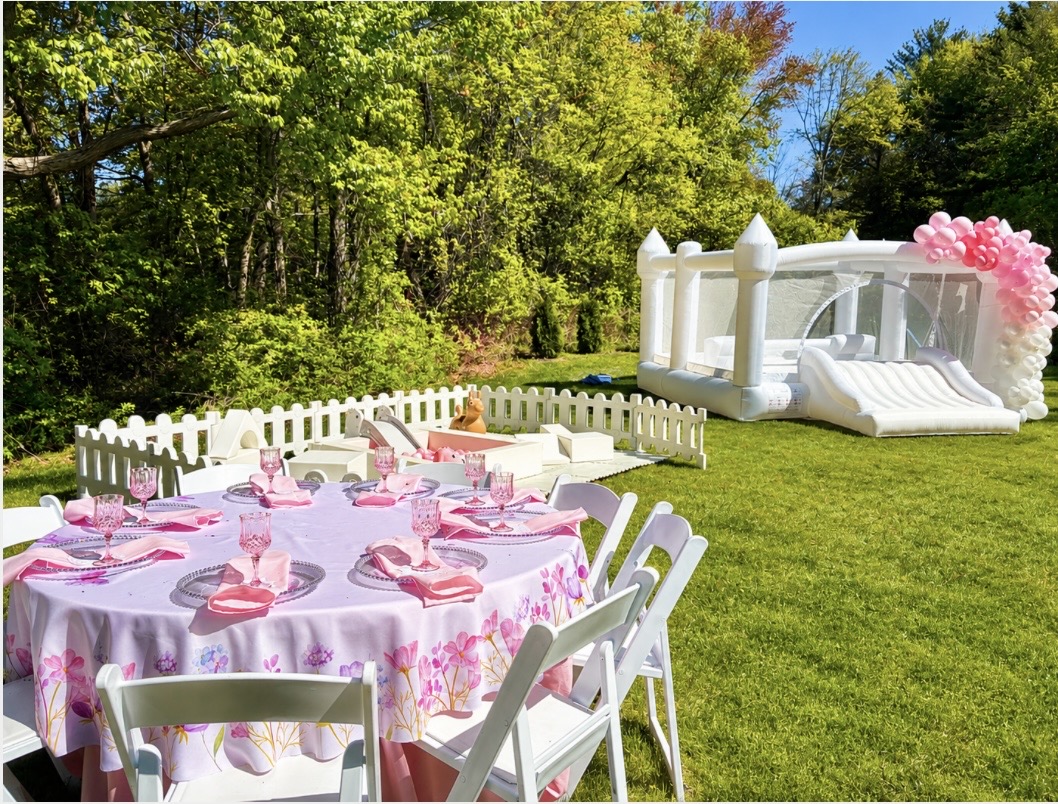 Pink floral table setup with white bounce castle and bubble dome