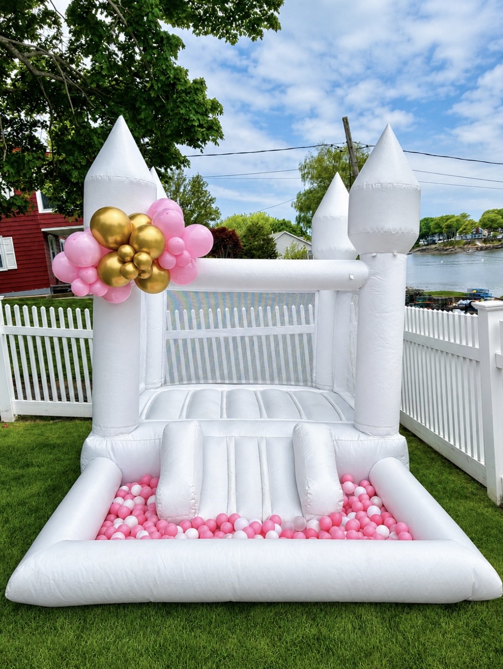 White bounce castle with pink ball pit and gold balloon accent