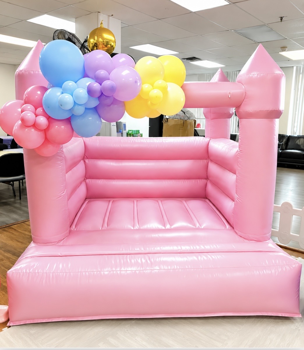 Pink bounce house with pastel balloon garland